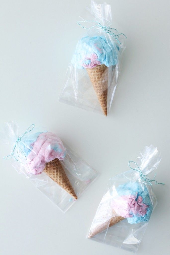 three ice cream cones wrapped in plastic and tied with blue ribbon on white surface, one is pink and the other is blue