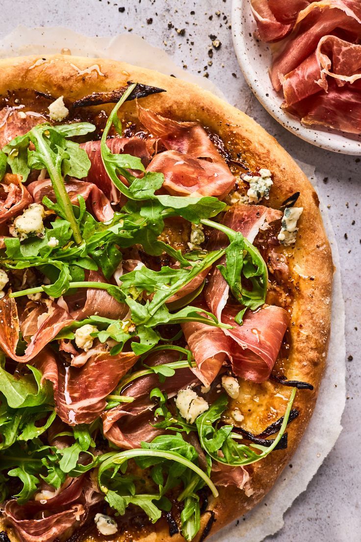 a pizza sitting on top of a pan covered in toppings next to meat and cheese