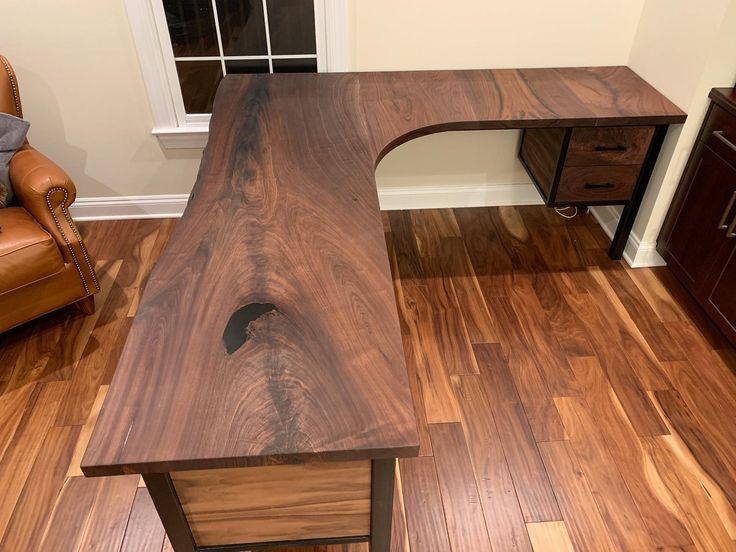 a wooden desk sitting on top of a hard wood floor next to a brown chair