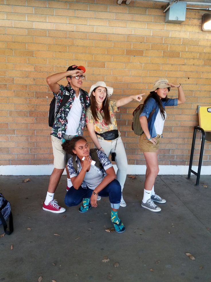 four people posing for a photo in front of a brick wall