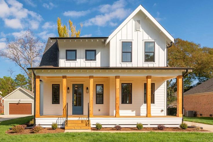 a white two story house sitting on top of a lush green field