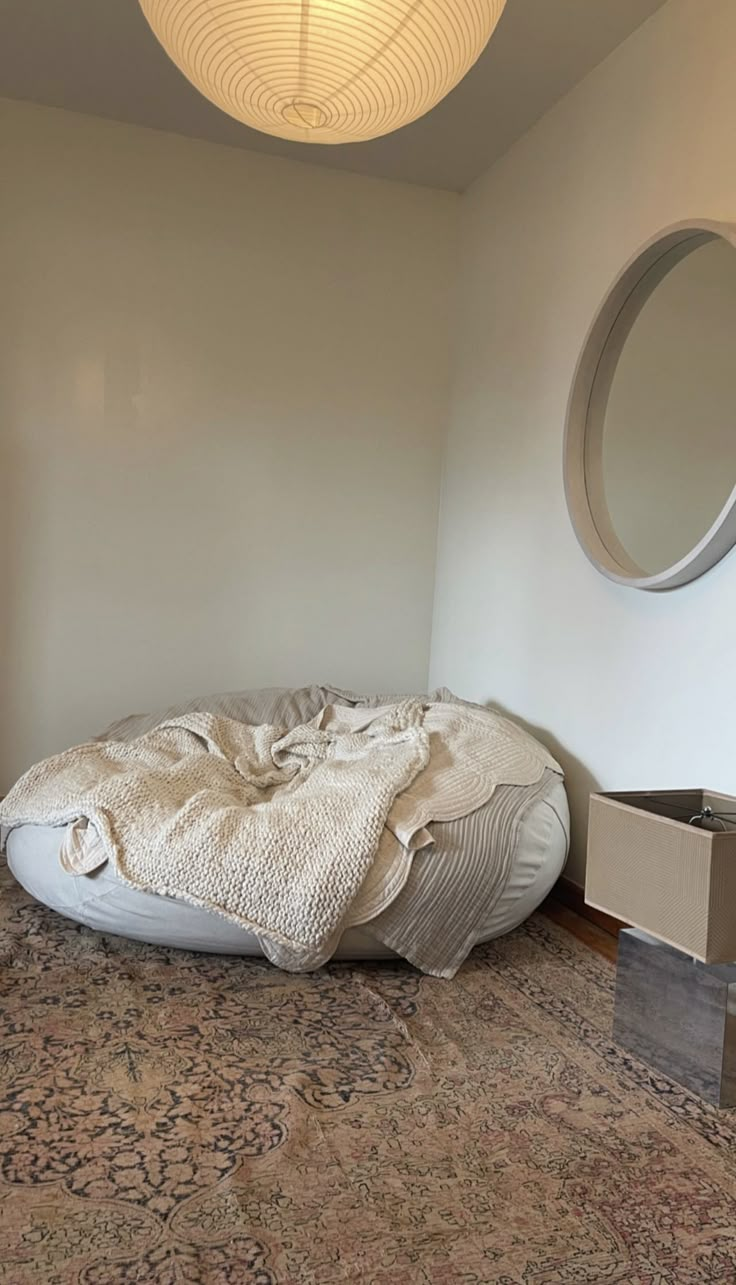 a large round bed sitting on top of a wooden floor next to a wall mounted mirror