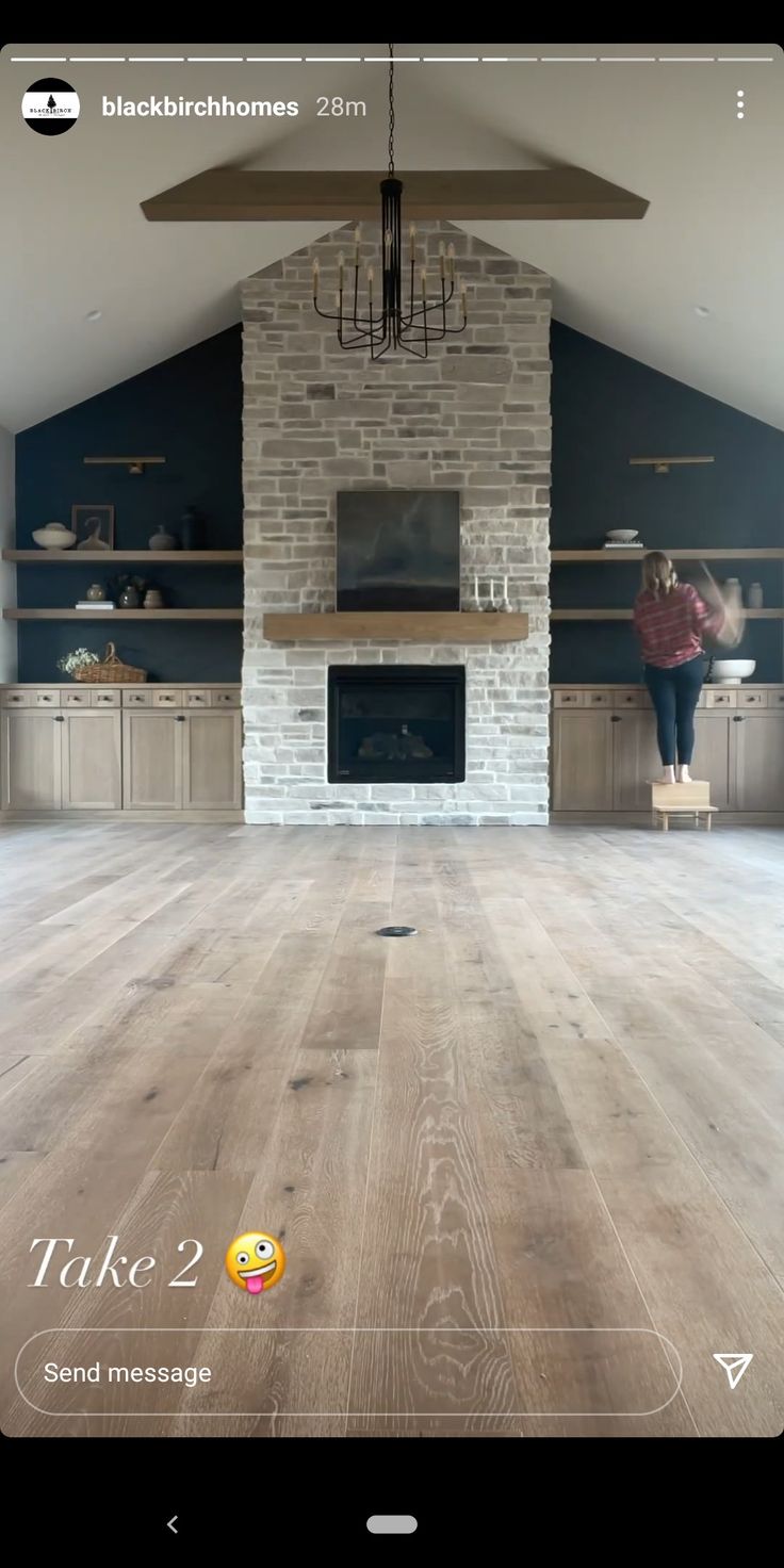 a woman is standing in the middle of an empty room with a fireplace and shelves