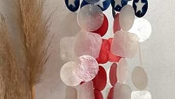 an american flag wind chime hanging on a wall next to a dried grass branch