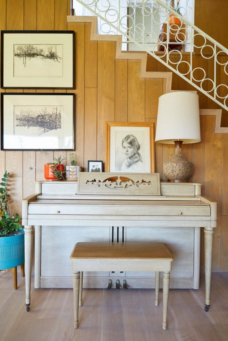 a white piano sitting in front of a stair case next to a blue potted plant