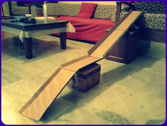 an open cardboard ramp sitting on top of a floor next to a table and couch