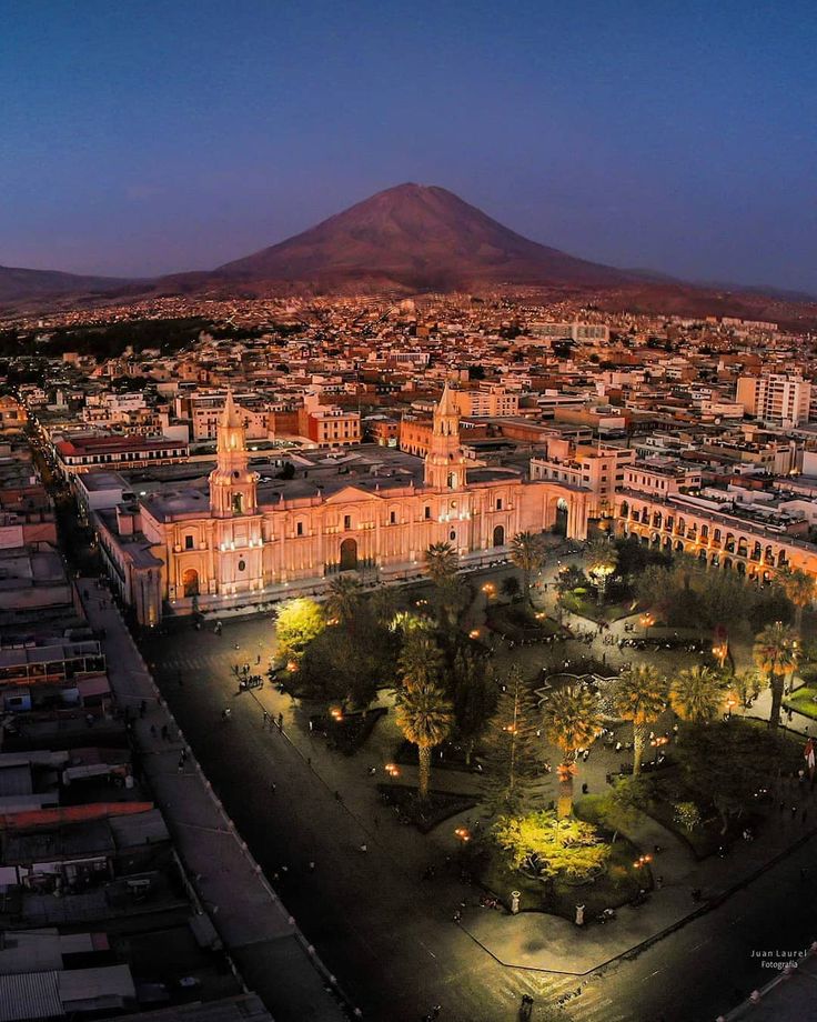 an aerial view of a city at night, with the volcano in the back ground