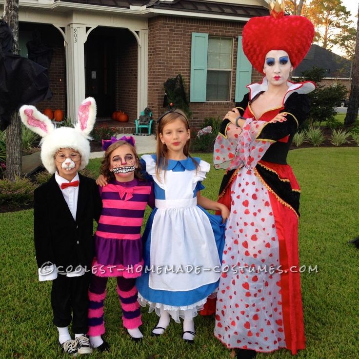 three children dressed up as alice and the rabbit in front of a house with their faces painted