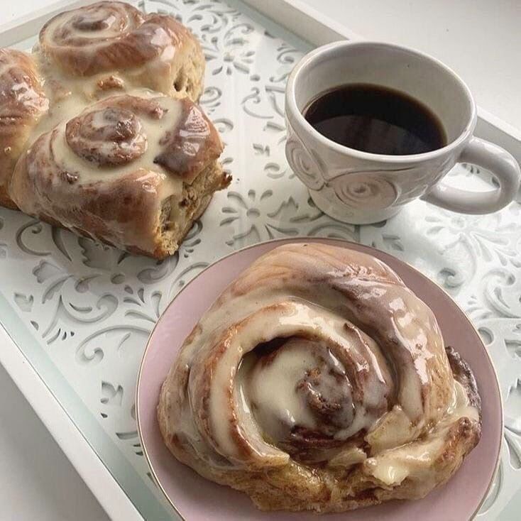 two pastries on a pink plate next to a cup of coffee