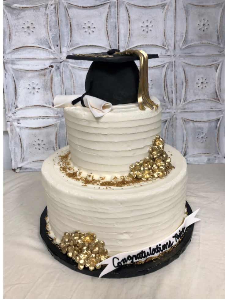 a white cake with gold decorations and a graduation cap on top