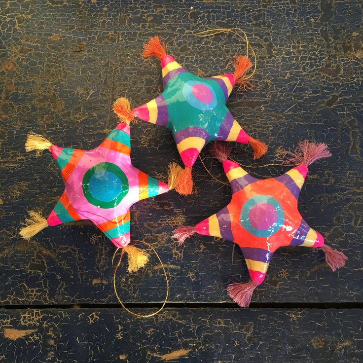 three star shaped kites with tassels on top of them sitting next to each other