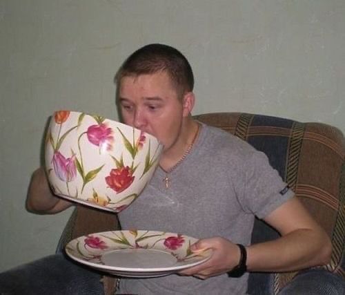 a man sitting in a chair drinking out of a cup and saucer while holding a plate