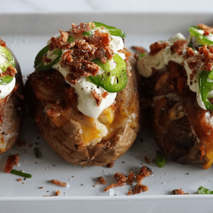 three loaded baked potatoes on a white plate