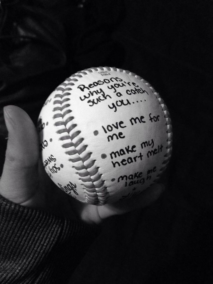 a person holding a baseball with writing on it