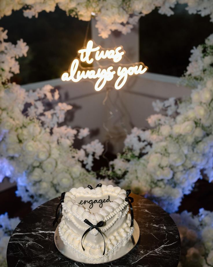 a white cake sitting on top of a table next to a sign that says it's always you