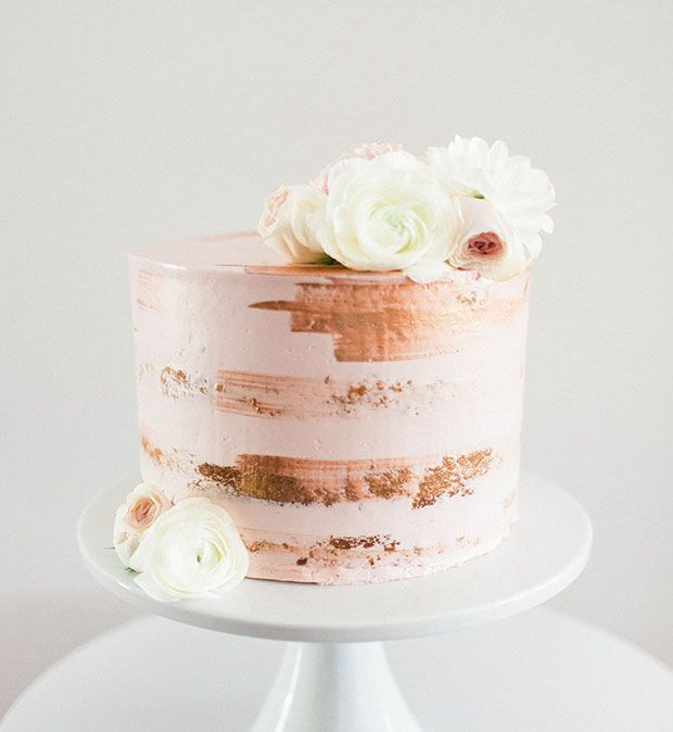 a white cake with pink and gold frosting sitting on top of a white plate