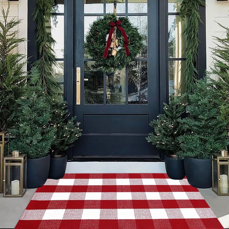 a red and white checkered rug on the front porch with evergreen trees in pots