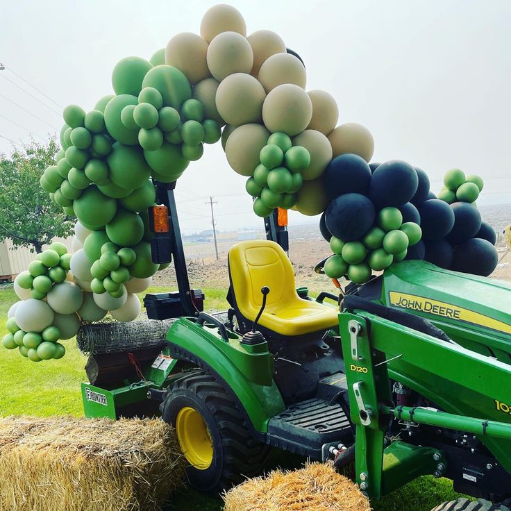 a tractor with balloons attached to it parked next to hay bales on the grass