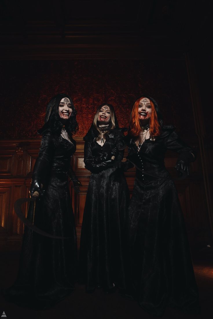 three women dressed in black standing next to each other with their faces painted like witches