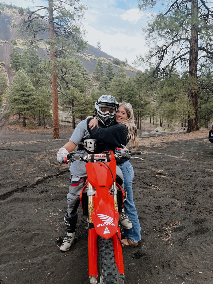 a man and woman are sitting on a dirt bike