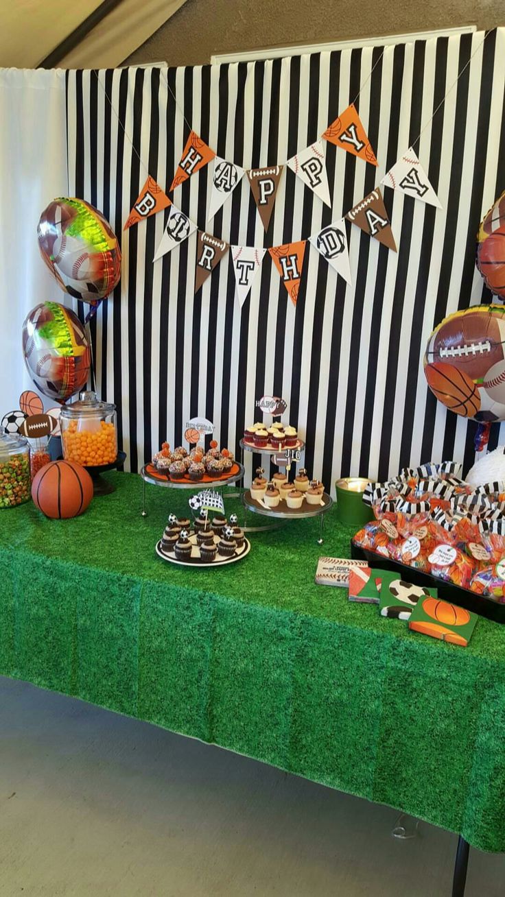 a green table topped with lots of food and desserts next to a striped wall