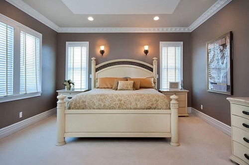 a large bed sitting inside of a bedroom next to two windows with white shutters