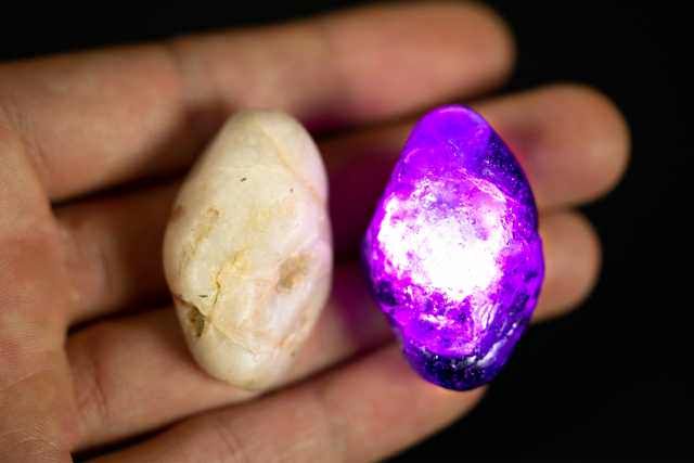 a person holding two different colored rocks in their hand, one is purple and the other is white