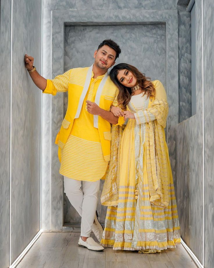 a man and woman posing for the camera in an empty room with walls painted yellow