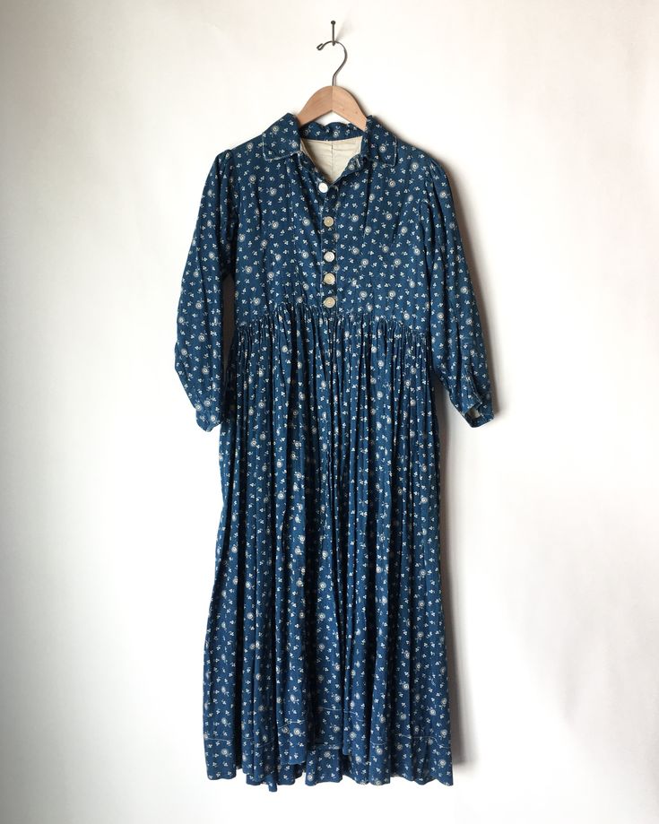 Rare calico indigo blue and white cotton prairie dress in great vintage condition. This dress is from the later part of the 1800’s/ early 1900’s and a lot of beautiful hand-stitching details are present. This is a wearable piece as well as a highly collectible and sought after garment. The gathering and pleating around the soar is incredible. The front has been opened to make it into a duster style. There's a little tear at the bottom of the dress in the back (see photo). MEASUREMENTS (flat) Arm Pastoral Cotton Prairie Dress For Daywear, Pastoral Prairie Dress In Cotton For Daywear, Vintage Cotton Yoke Dress, Vintage Cotton Dress With Yoke Detail, Vintage Cotton Dress With Buttons For Daywear, Spring Cotton Prairie Dress With Buttons, Cotton Vintage Dress With Buttons For Daywear, Cotton Prairie Dress For Fall Daywear, Vintage Blue Victorian Dress For Spring