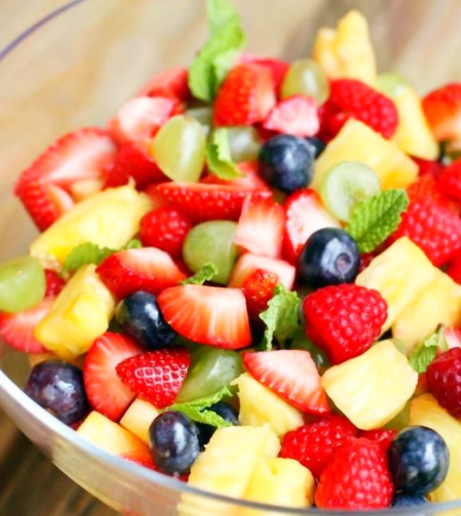 a glass bowl filled with fruit on top of a wooden table