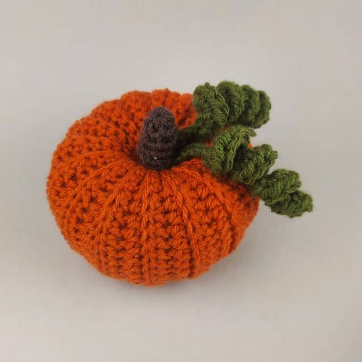 an orange knitted pumpkin sitting on top of a white table