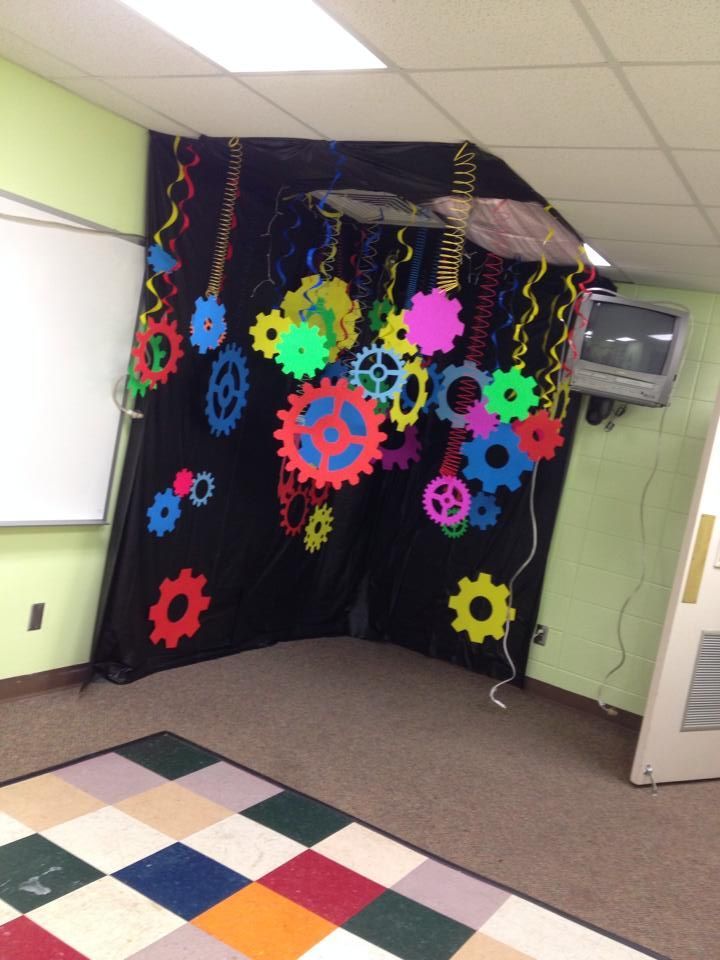 an office cubicle decorated with colorful gears and streamers hanging from the ceiling in front of a projector screen