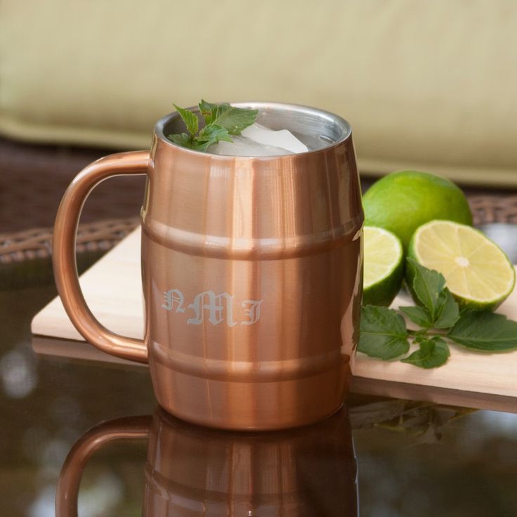 a copper mug sitting on top of a table next to limes