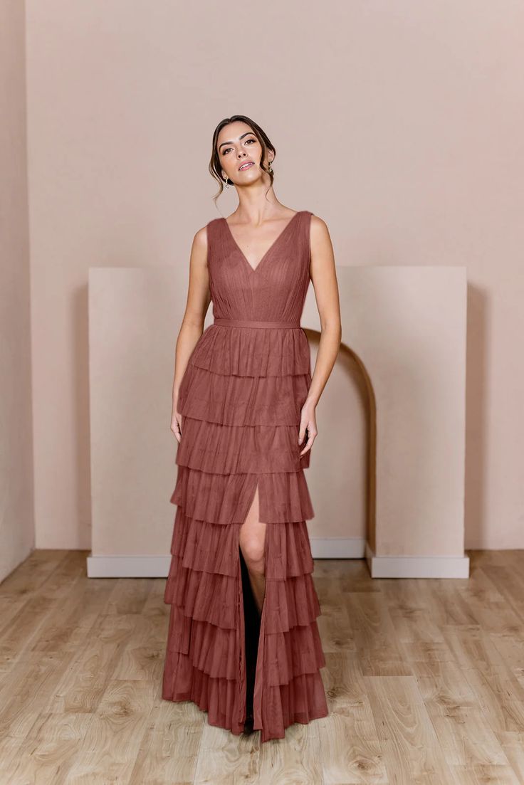 a woman in a long dress standing on a wooden floor