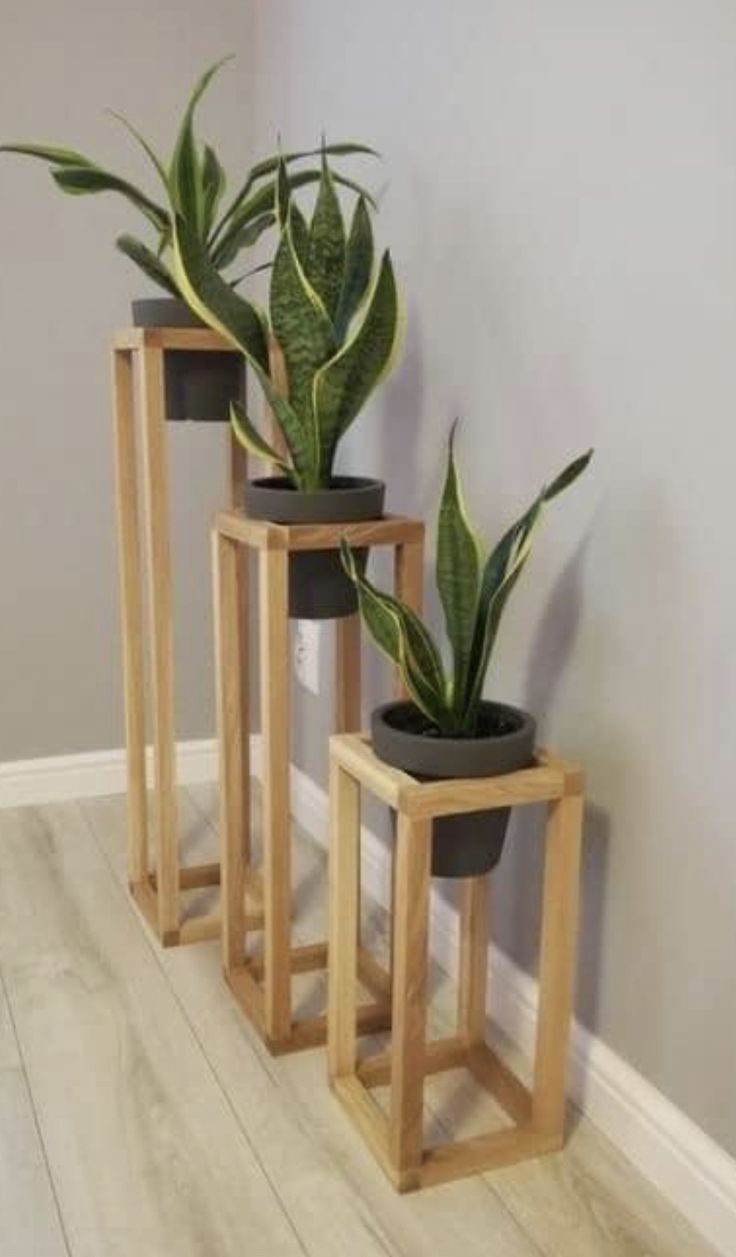 three wooden planters with plants in them sitting on the floor next to a wall