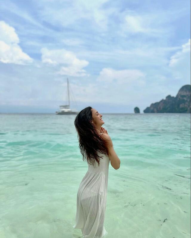 a woman standing in the ocean with her head tilted back and looking up to the sky