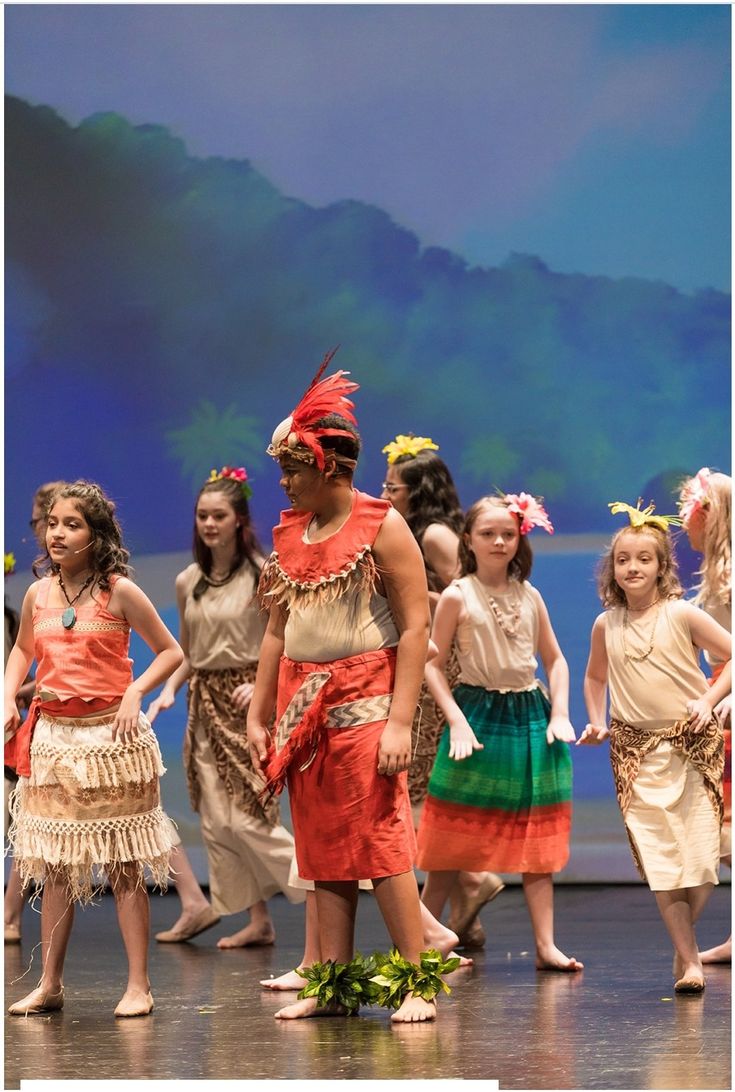 a group of young children standing on top of a stage wearing native american clothing and headdress