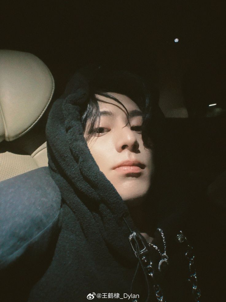 a young man with his eyes closed sitting in the back seat of a car at night