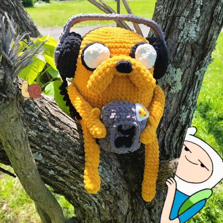 a crocheted dog hat hanging on a tree branch with a cartoon character in the background