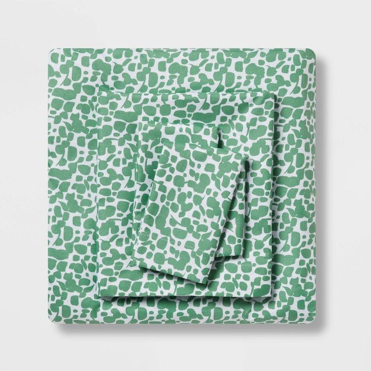 a green and white print sheet set on top of a bed