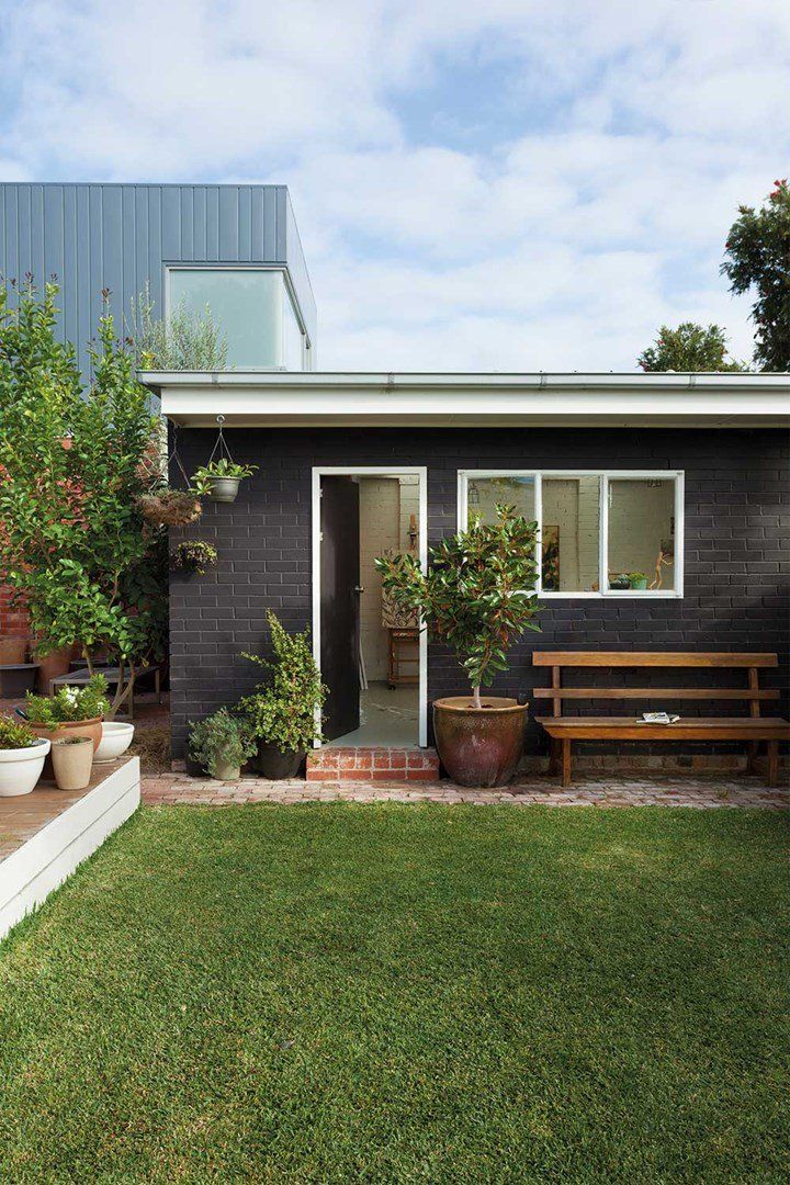 a small house with potted plants and a bench