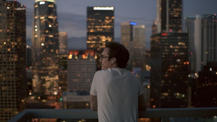 a man standing on top of a building looking out at the city lights and skyscrapers