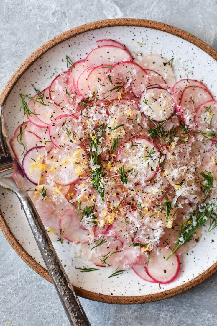 a white plate topped with sliced radishes and cucumbers next to a fork