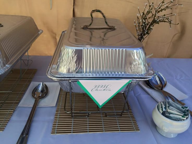 a table topped with silver trays and serving utensils on top of a blue table cloth