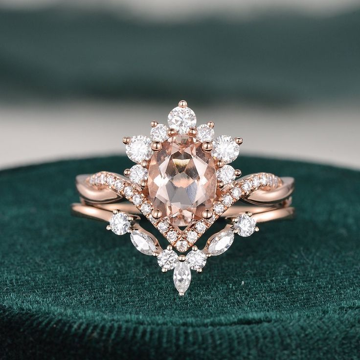 an engagement ring with a pink morganite surrounded by white diamonds on a green velvet cushion