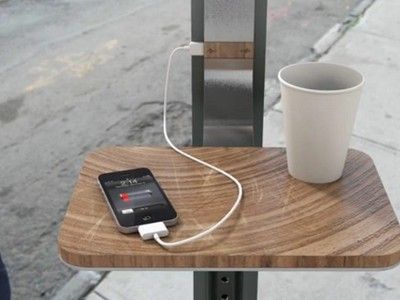 an iphone charging on a wooden table next to a cup