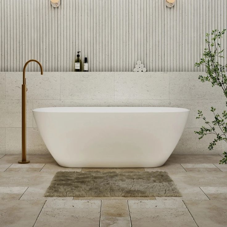 a white bath tub sitting on top of a tiled floor next to a green plant