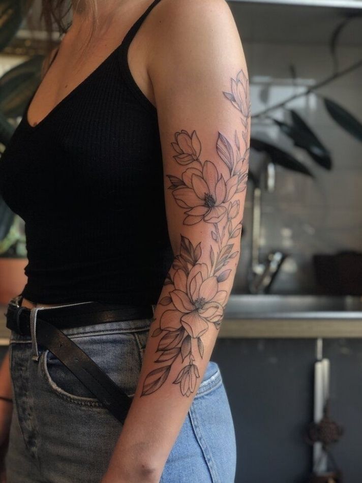 a woman with a tattoo on her arm standing in front of a kitchen counter top