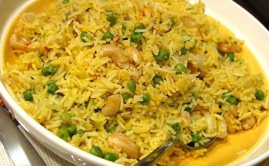 a white bowl filled with rice and peas on top of a table next to silverware