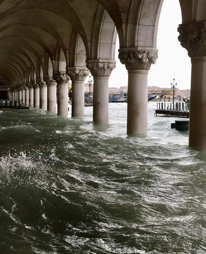 the water is rushing under an old building with pillars and arches on it's sides